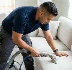 Professional upholstery cleaning technician using an extraction wand to deep-clean a fabric sofa, Cleveland, OH.