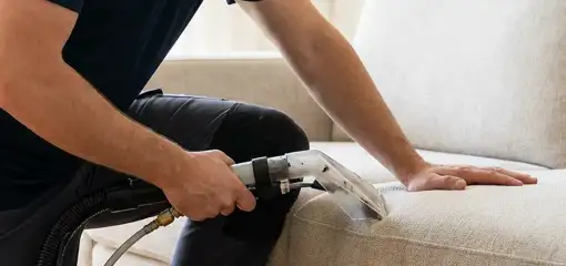 Professional upholstery cleaner deep-cleaning a fabric sofa with a handheld extraction tool, Cleveland, OH.